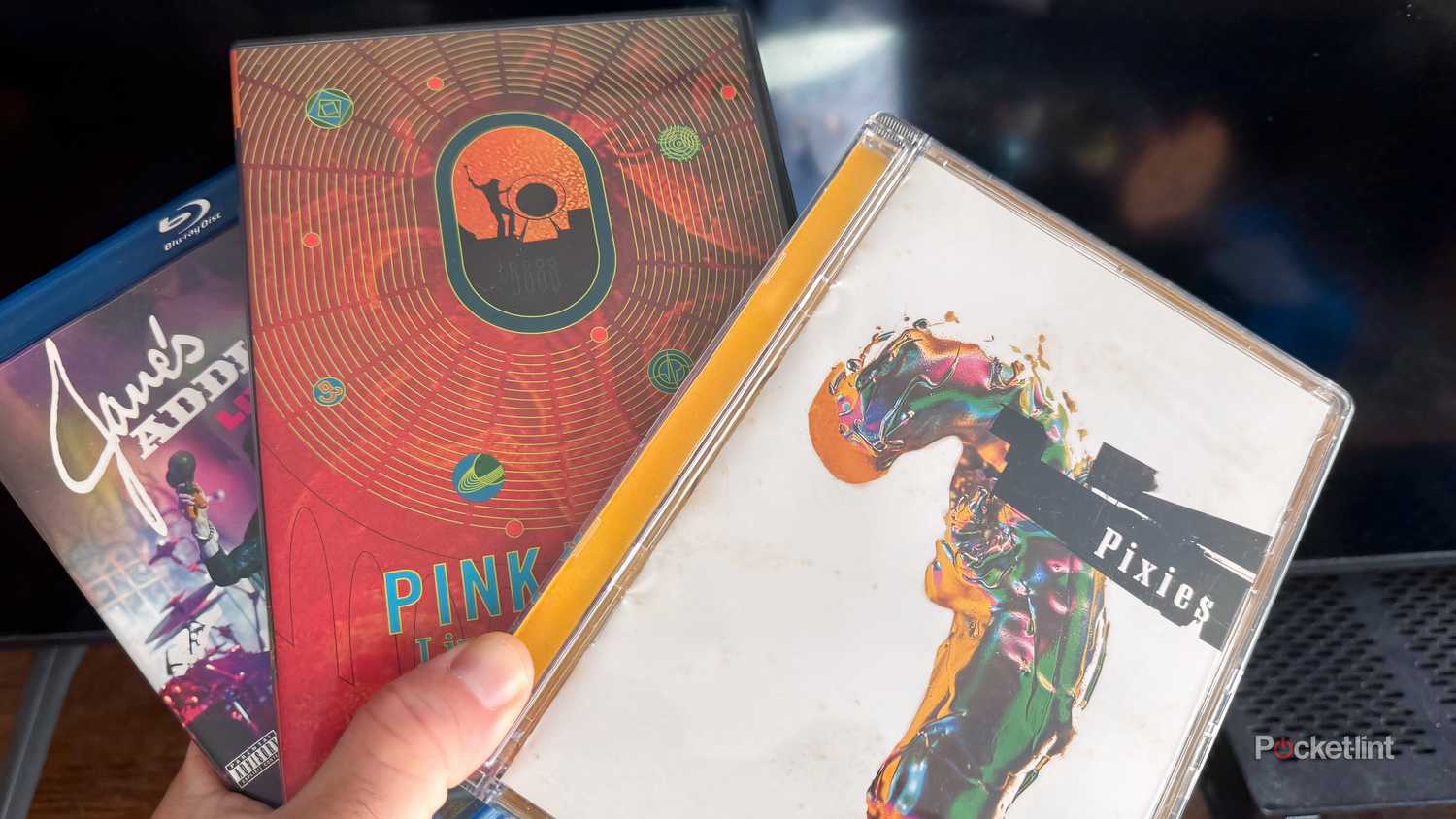 Close-up of and holding multiple concert DVDs.