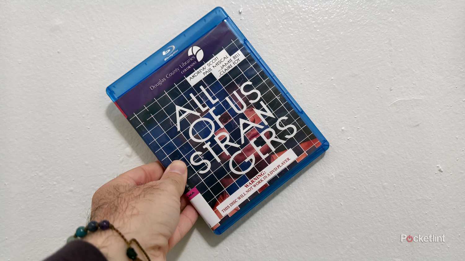 All of Us Strangers Criterion disc held in front of white wall.