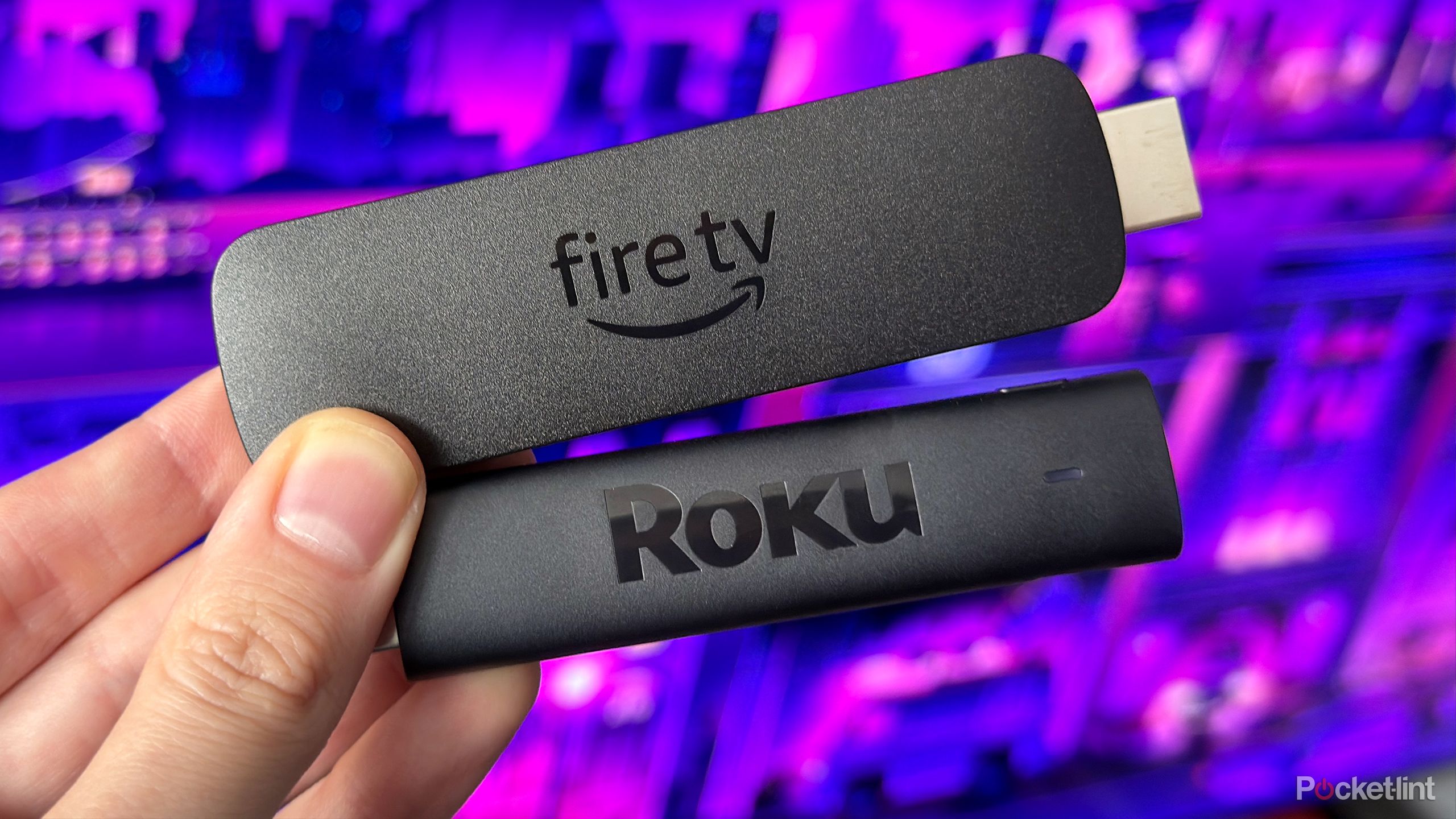Person holding Roku Streaming Stick 4K and Fire TV Stick 4K Max.