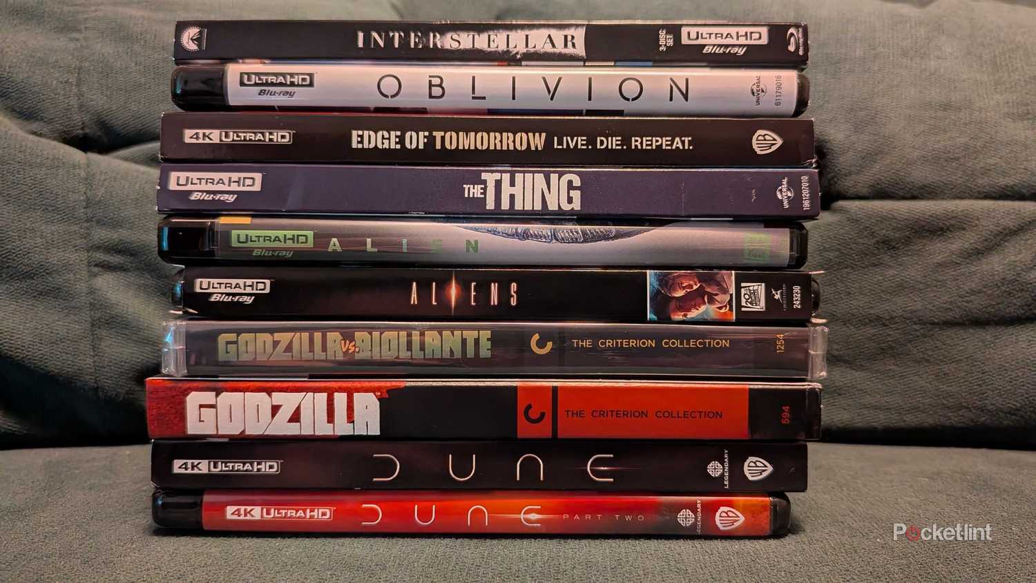 A stack of 4K Blu-ray discs on a couch.